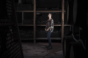 Donna tra bottiglie di vino in una cantina