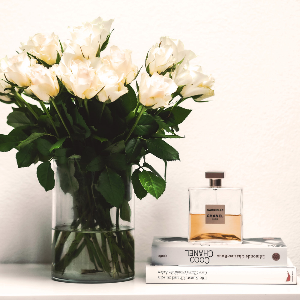 tavolo con libri, bottiglia profumo e fiori