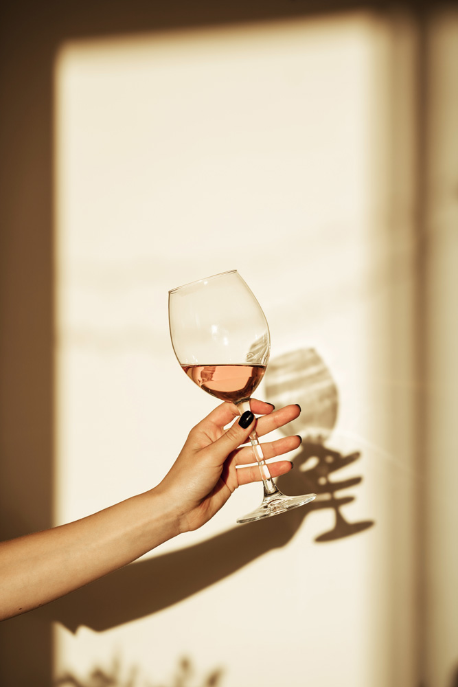 Mano di donna con bicchiere di vino in controluce