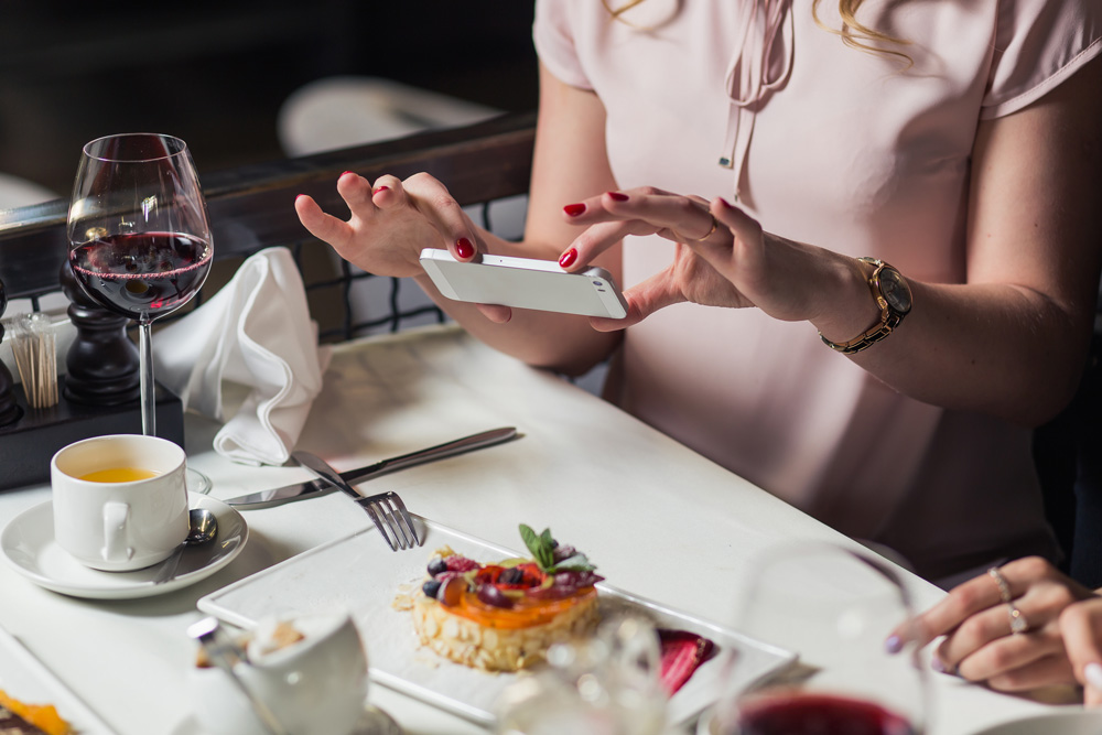 donna che fotografa tavola con dolce e bicchiere di vino